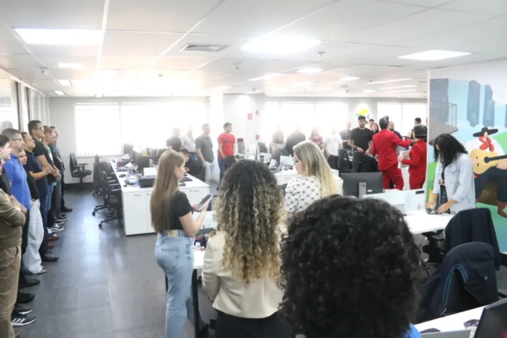 Funcionários reunidos em escritório participam de palestra sobre segurança com objetos cortantes, prevenção de acidentes e saúde ocupacional.