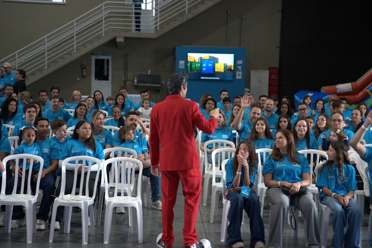 Palestrante conduz atividade interativa com jovens e famílias durante evento educativo em auditório.