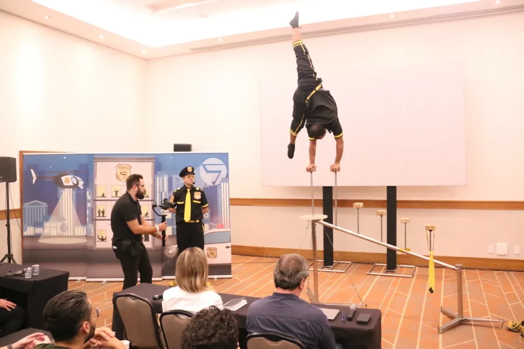 Apresentação de equilíbrio com performer sobre estrutura metálica em evento corporativo com foco em percepção de risco