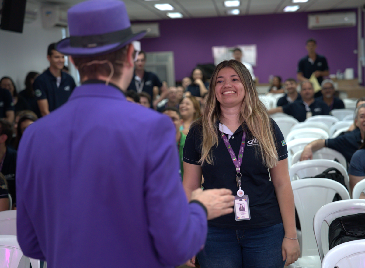 Colaboradora participa de apresentação durante evento da SIPAT em auditório corporativo decorado na cor roxa